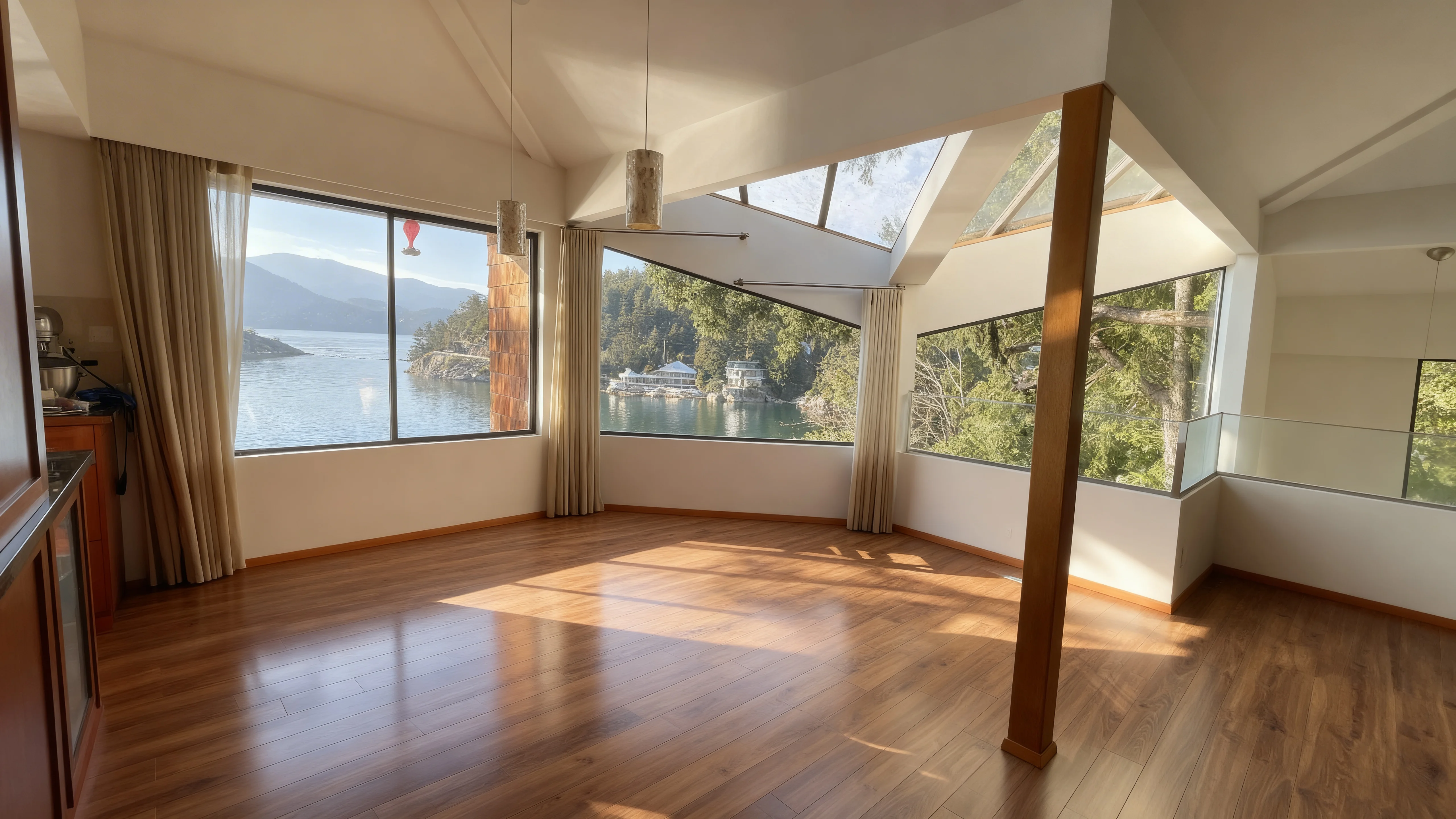 Bright vaulted great room with panoramic windows over a calm BC inlet and forested hills